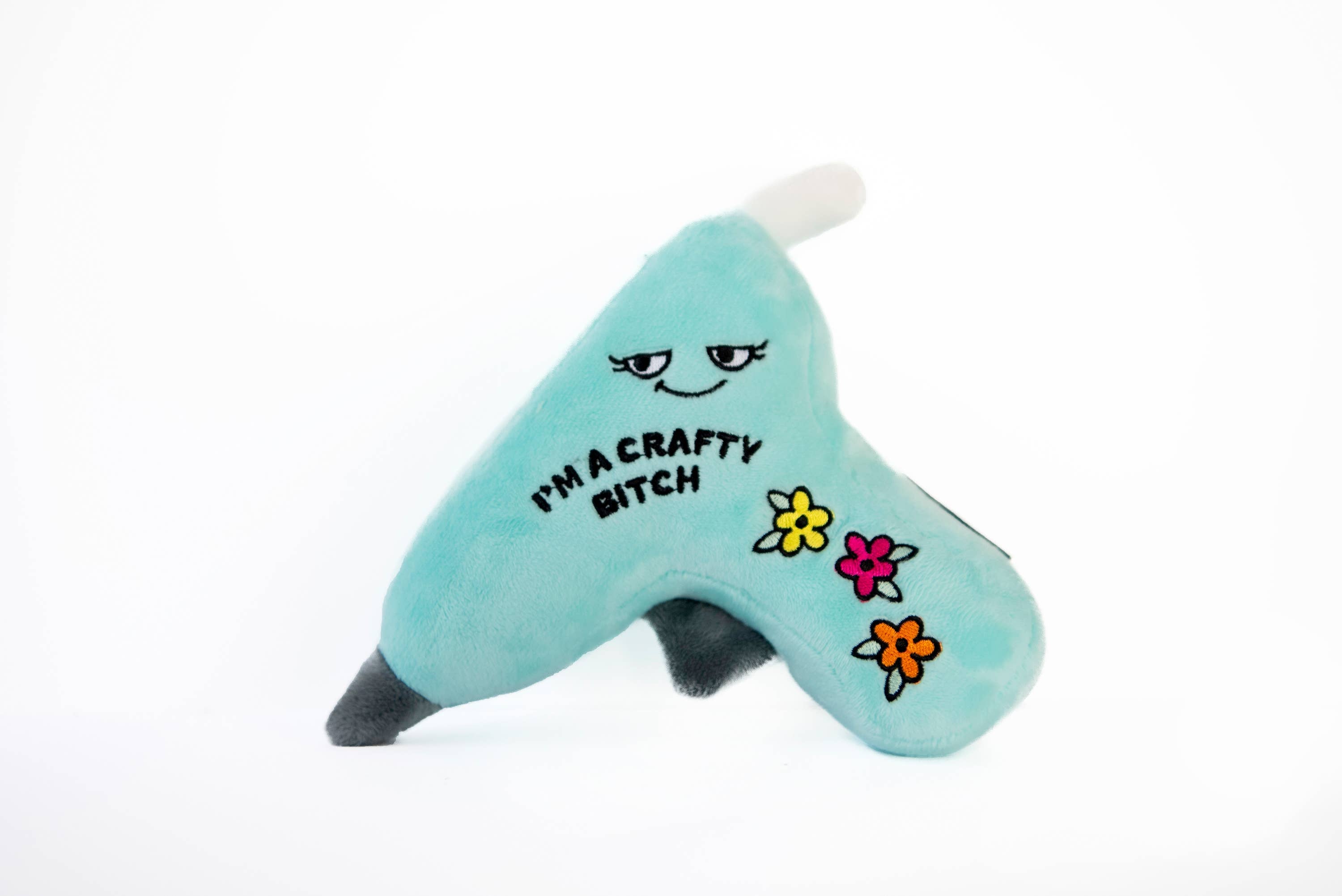 A blue glue gun plushie with a smiley face, three flowers, and black embroidered text that says 'I'm a crafty bitch.