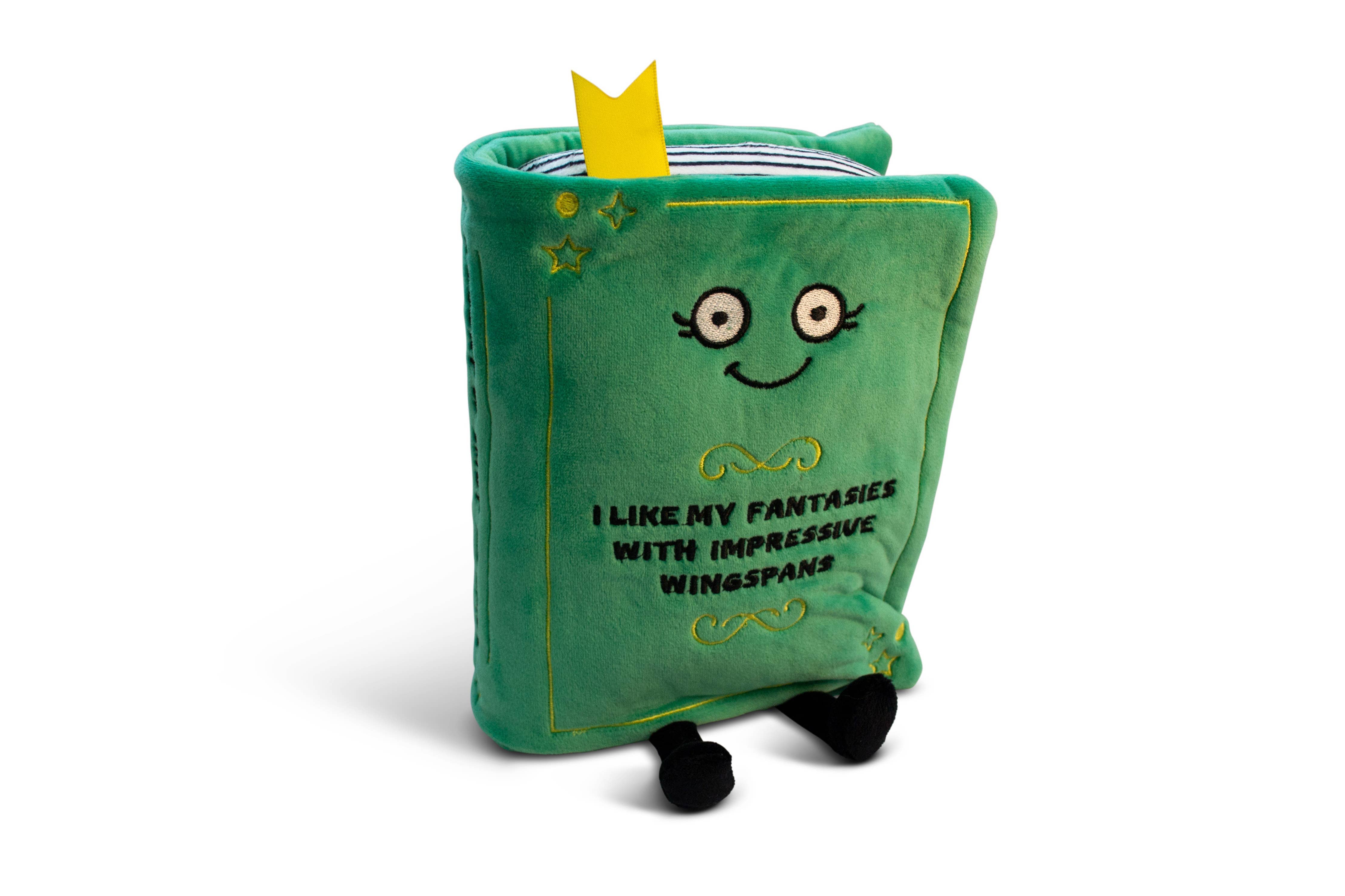 A green plush with a smily face and embroidered black text that reads 'I like fantasies with impressive wingspans.' The plush has black legs sticking out and a yellow bookmark peeking from the top.