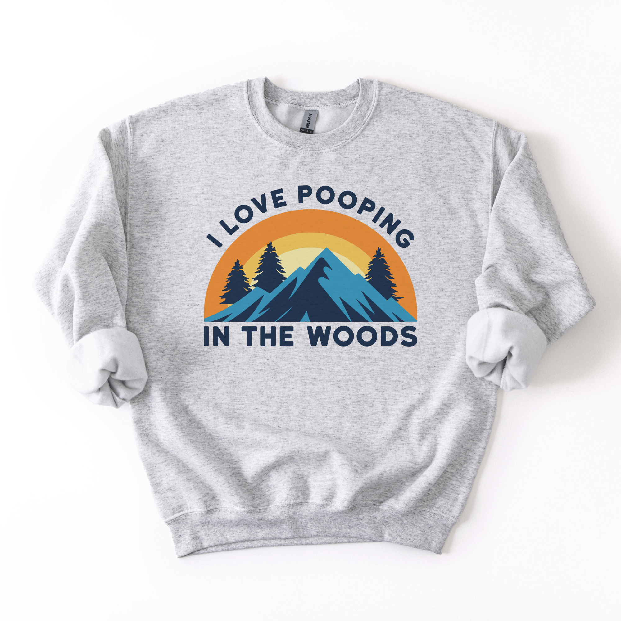 A gray crew sweatshirt with a graphic that says 'I Love Pooping in the Woods' with a background of a sunset and pine trees.