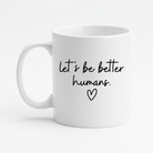 White mug with 'let's be better humans' text and heart symbol on a white background