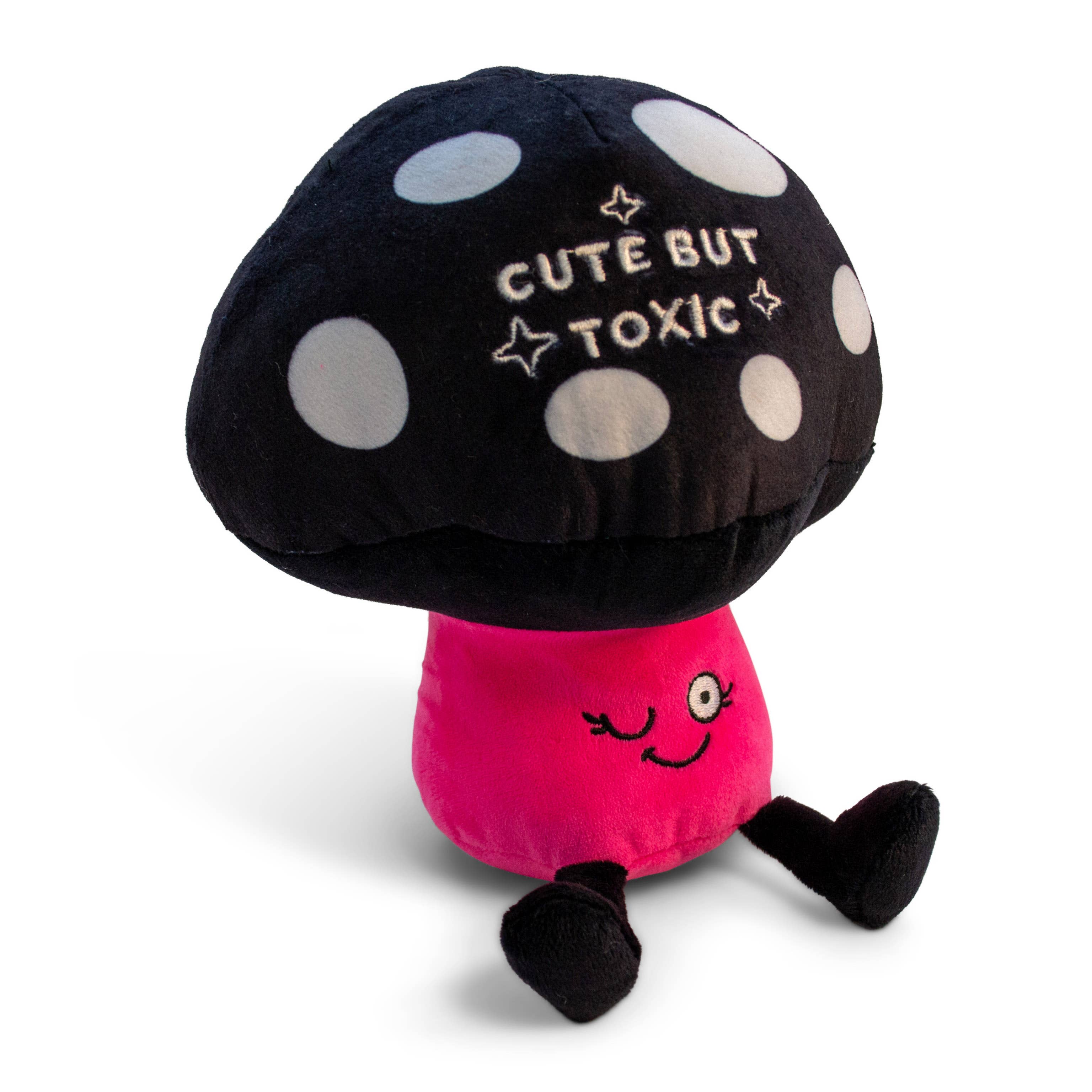 A mushroom plush with a black and white polka dot top and white text that says "Cute but toxic." The stem is pink with a winking smiley face, and the plushie has black legs sticking out.