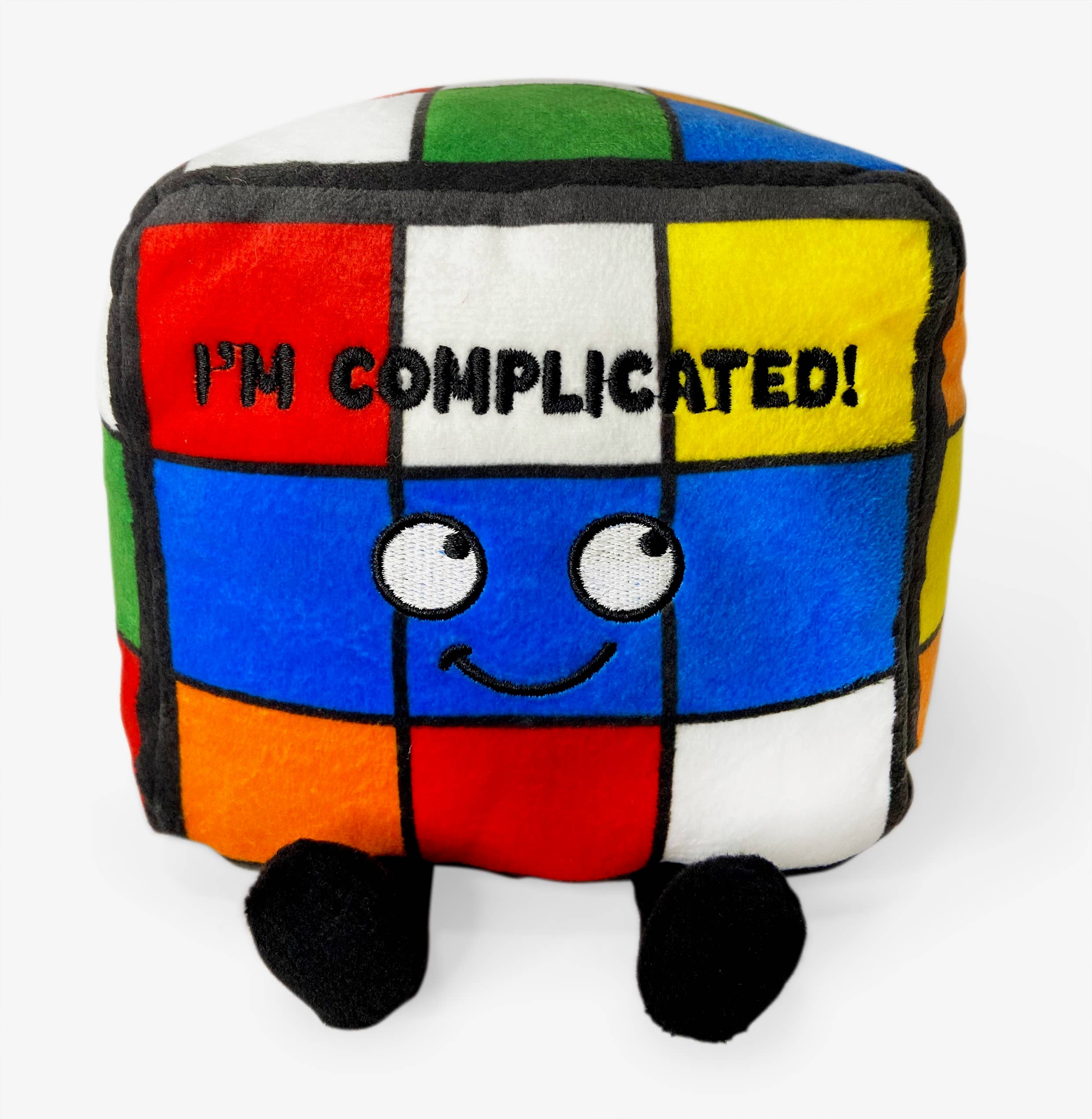 A rainbow puzzle cube plushie with a smiley face and black text that says "I'm complicated." The plushie has black legs sticking out.