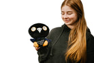 Woman holding a black and blue raven plushie with a white beak and white and yellow eyes. Its wings are holding a black heart with the white text "Nevermore in love with you." The raven has yellow legs with a black "xoxo" on the right foot.