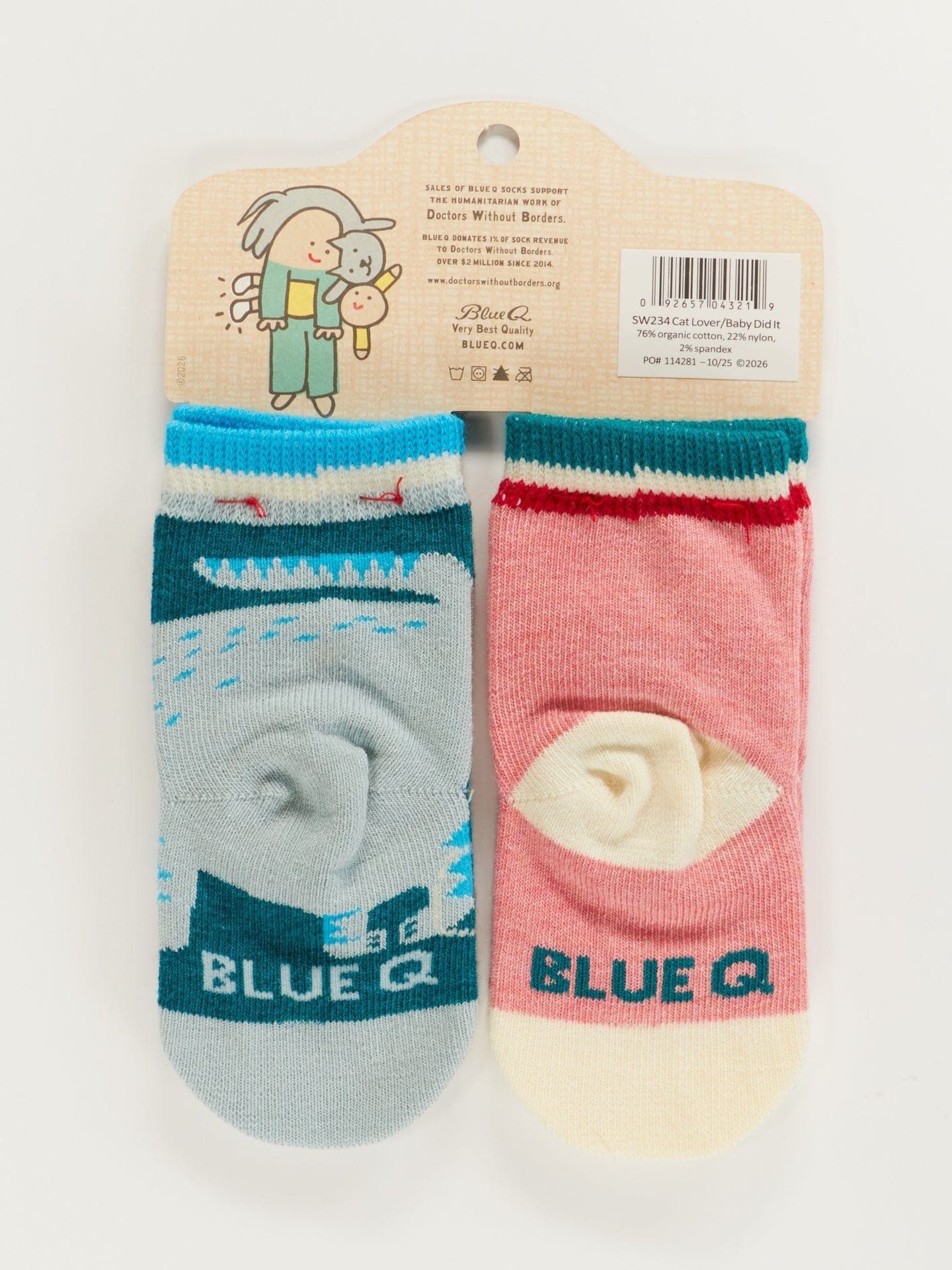 A close-up of a pair of teal and white baby socks featuring an illustration of a cat and the text 'the baby did it.' in a playful font.