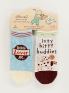 Two pairs of Blue Q baby socks; one pair is light blue with a 'Dog Lover JR.' patch, and the other is white with brown accents featuring a dog illustration and the text 'itty bitty buddies'.
