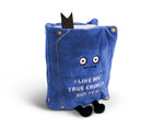 Blue plush book sitting up, with a straight face and white embroidered words that say 'I like my true crimes solved.' Black legs sticking out bottom and black bookmark peeking out the top.