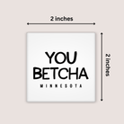 A square white magnet with the phrase “YOU BETCHA MINNESOTA” in black text, shown on a light beige background with dimension arrows labeling it 2 inches by 2 inches.