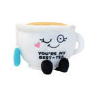 A plush toy designed to look like a smiling tea cup with a playful expression, featuring one winking eye and a small pink heart on its cheek. The cup is filled with a soft, plush 'tea' top, and a blue tea bag dangles from the side. The front of the plush displays the phrase 'YOU’RE MY BEST-TEA' in bold, embroidered letters. It has small black legs and a handle on one side, adding to its adorable and cozy charm.