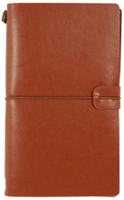 A brown leather journal with a textured cover is closed with a slim elastic band. A strap closure adds to its rustic and elegant appearance.