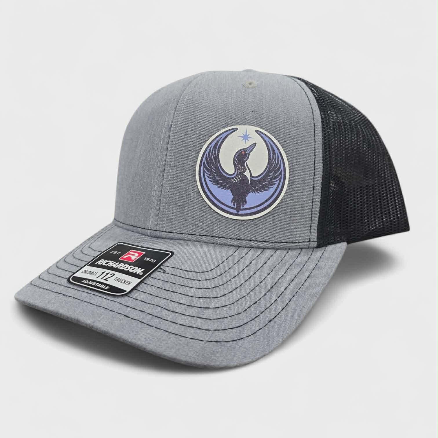 Gray and black trucker hat with a logo of a rebel loon on a light gray background