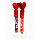 Two tubes of red matte liquid lipstick with shiny heart-shaped caps stand on a white pedestal. The packaging is sleek and vibrant, evoking a romantic tone.