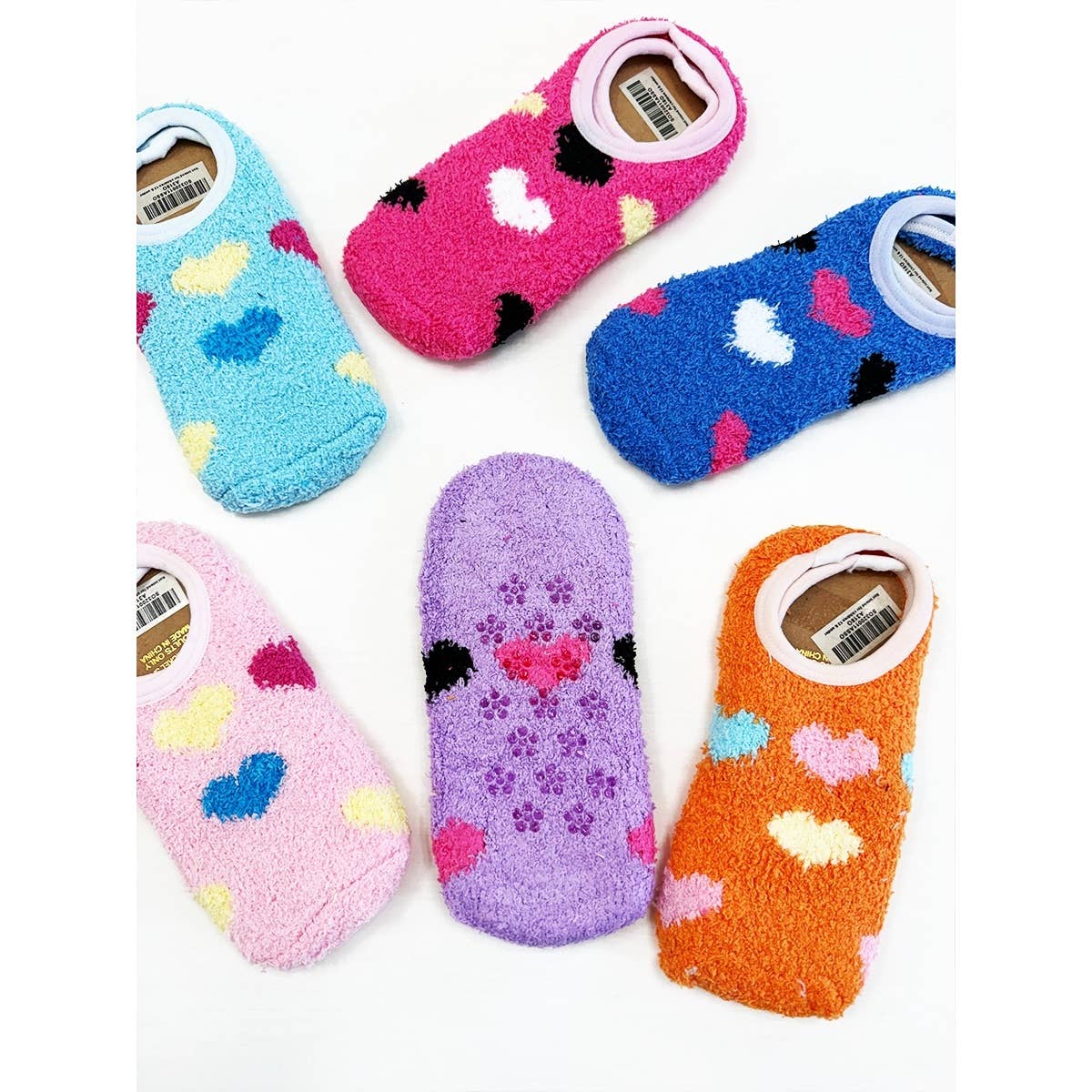 Six fuzzy ankle socks arranged in a circle, each a different color. They feature vibrant heart and paw print patterns, conveying a playful and cozy vibe.
