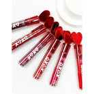 Six tubes of red matte liquid lipstick are laid diagonally on a white surface. They feature heart-shaped caps and the text "XOXO" on the tubes.