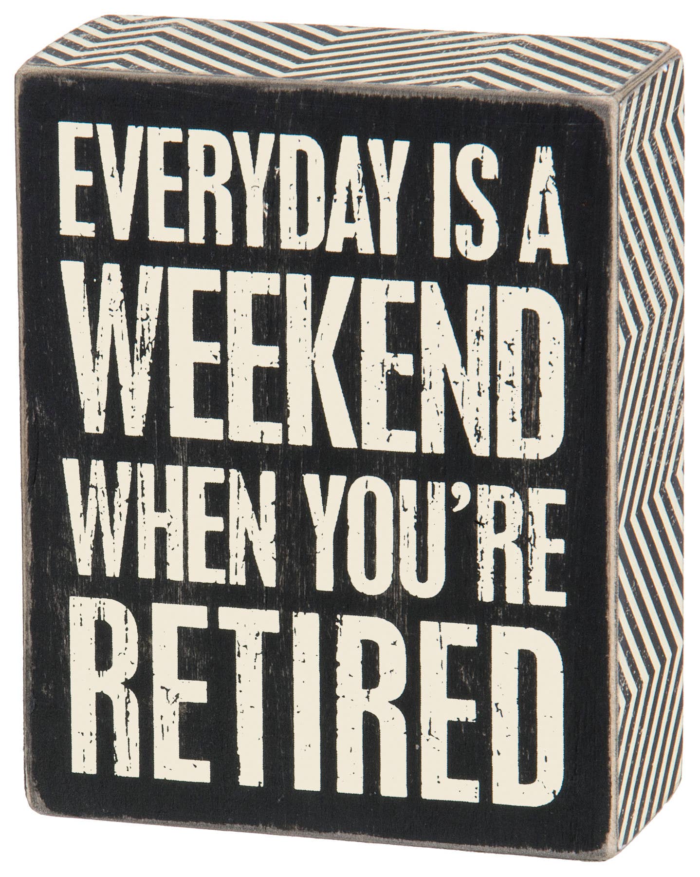 A square black wooden box sign with white capitalized text that reads 'EVERYDAY IS A WEEKEND WHEN YOU’RE RETIRED.' The sign features a distressed vintage finish and a decorative black and white zigzag pattern on the side panels.