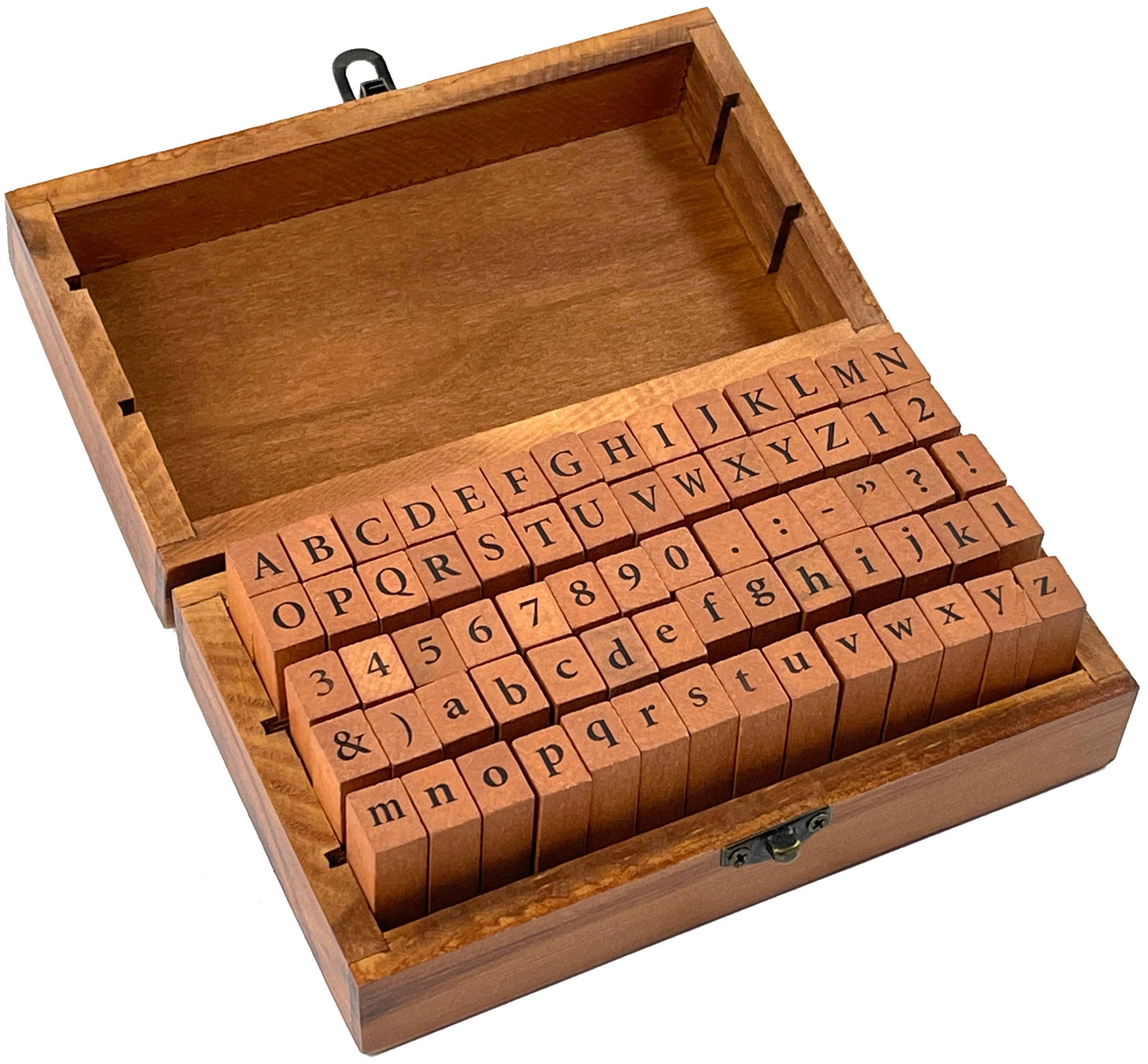 A wooden box with an open lid displays alphabet and number rubber stamps. The orderly arrangement conveys a sense of organization and creativity.
