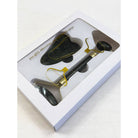 Boxed facial massage set with a black jade roller and heart-shaped gua sha tool, visible through a clear window. The packaging is sleek and elegant.