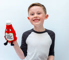 Child holding a ketchup bottle plushie with a smiley face and a white belly featuring black text that says "I put ketchup on my ketchup." It has a white lid and black legs sticking out.