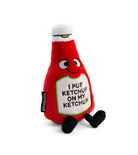 A ketchup bottle plushie with a smiley face and a white belly featuring black text that says "I put ketchup on my ketchup." It has a white lid and black legs sticking out.