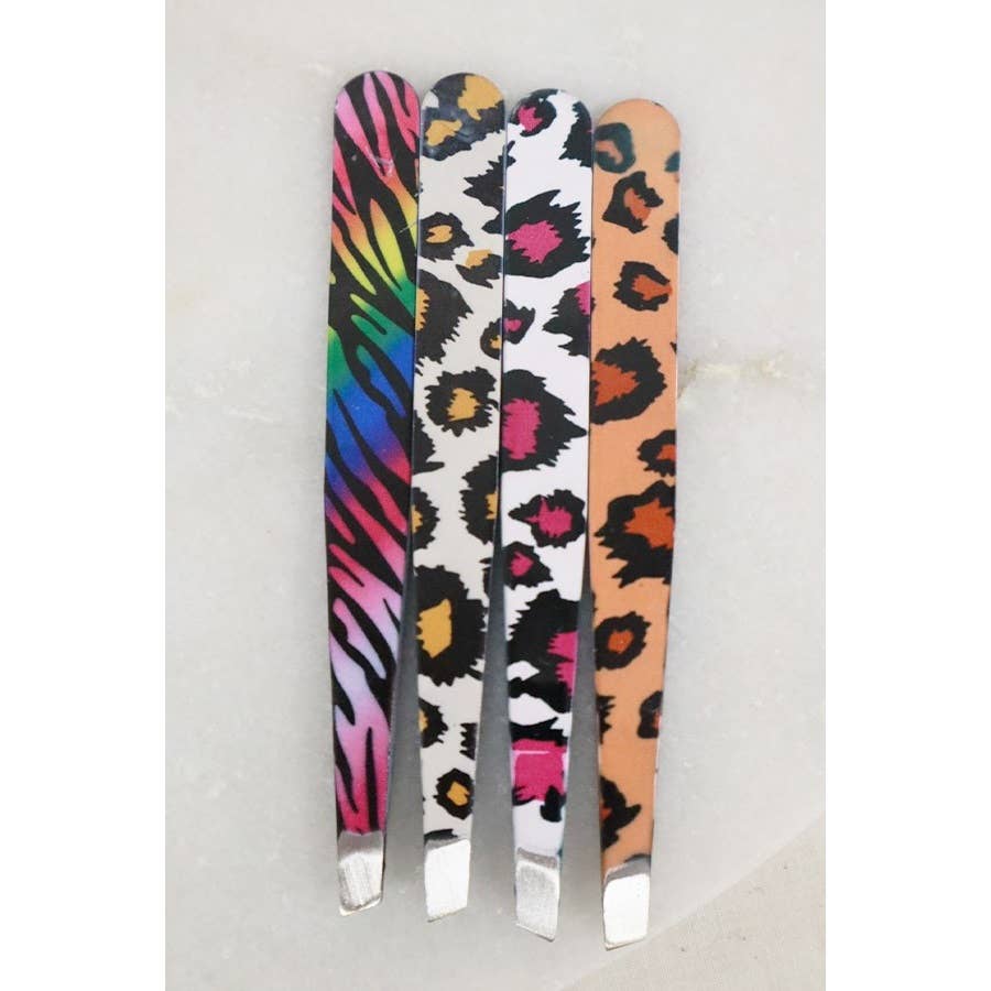 Four pairs of slanted tweezers lined up together, featuring different animal print patterns including rainbow zebra stripe, black and white leopard print, and classic tan leopard print.