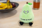 A green pear plushie with a smiley face, brown stem, and a green leaf on top. The front features black text that says "Grow a pear" and the plush has black legs sticking out.