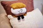 A plushie shaped like a s'more with a winky face. The chocolate layer features white lettering that reads "I love you s'more!"