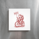Fridge magnet with a red illustration of a frog on a bicycle holding a 'RESIST' sign, placed on a metallic surface.