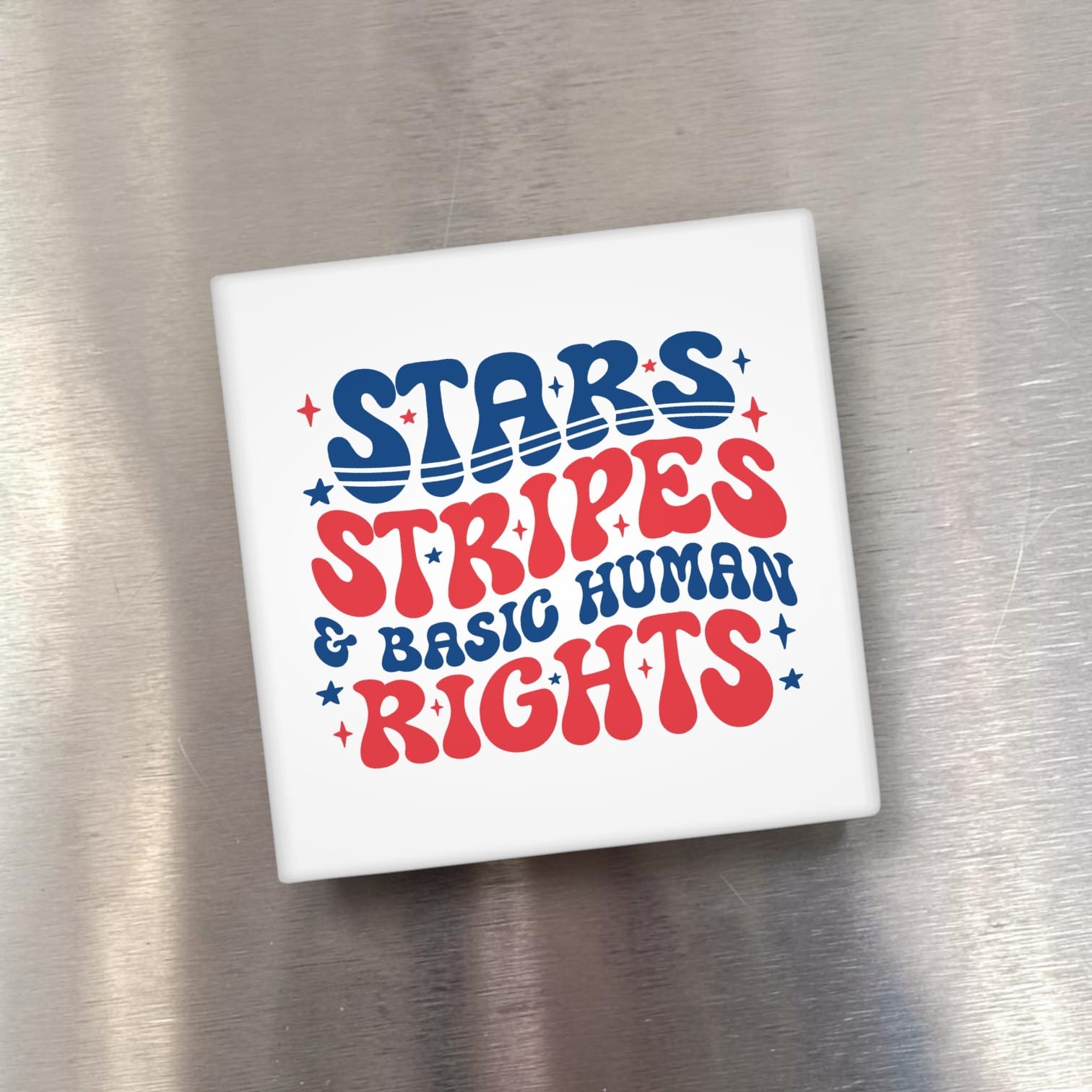 White square object with 'Stars Stripes & Basic Human Rights' text on a metallic surface