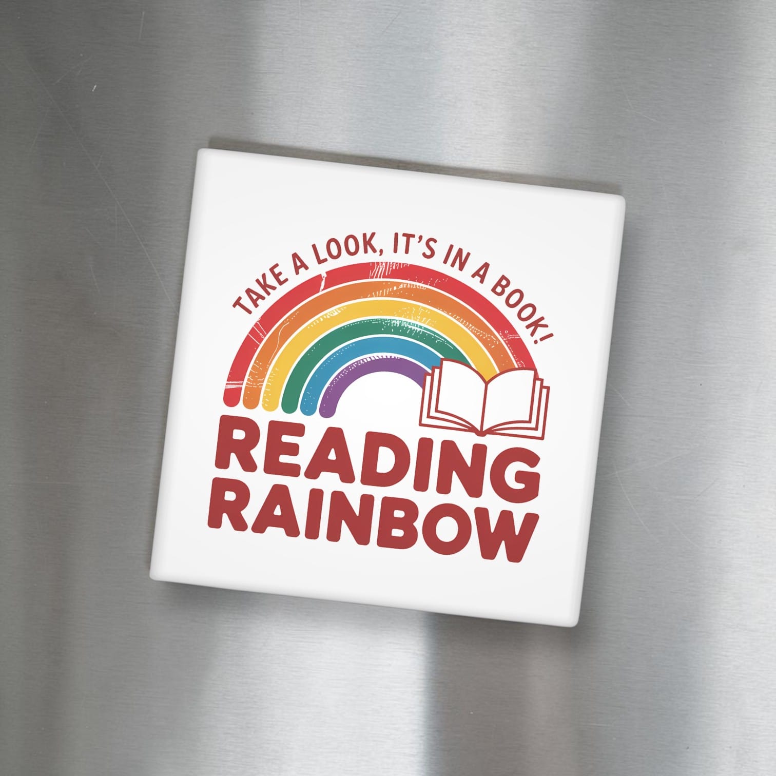 White square magnet with rainbow and text on a metallic surface - Take a Look It's In a Book Reading Rainbow"