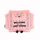 A pink plush pillow shaped like a tick with a round, soft body. It has a smiling face and black text on the front that reads 'Welcome to the Shit Show,' giving it a humorous and quirky appearance.