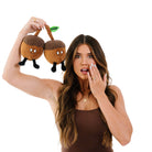 woman holding Two brown acorn plushies with smiley faces, their stems touching. A green embroidered leaf connecting them features the word 'deez' in black text. Both acorns have black legs sticking out from the bottom.