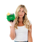 woman holding A plushie green dumpster fire with a smiley face, black embroidery that says 'i'm fine... everything is fine!' and black legs sticking out from the bottom. Yellow flames are coming out from the top."